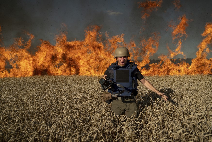 Photojournalist Evgeniy Maloletka runs from a blaze in a burning wheat field while on assignment after Russian shelling, a few kilometers from the Ukrainian-Russian border in the Kharkiv region, Ukrai ...