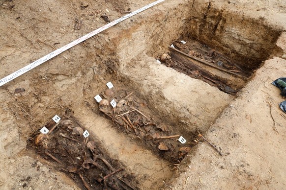 Workers are pictured at the excavation site during the exhumation of the remains of Soviet soldiers buried in the city center of Vievis, Lithuania, on July 20, 2026. A wartime grave-site outside Lithu ...