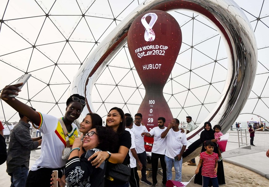 epa10117581 Soccer fans take selfies in front of the Qatar 2022 FIFA World Cup countdown clock, marking 100 days to go till the beginning of the tournament in Doha, Qatar, 12 August 2022. EPA/NOUSHAD  ...