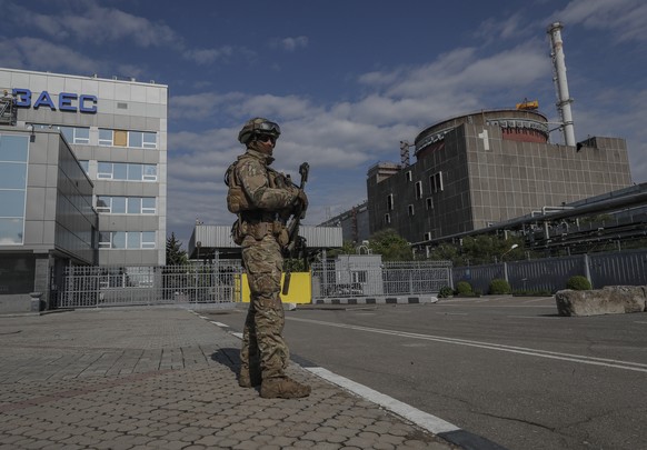 epa09921718 A picture taken during a visit to Mariupol organized by the Russian military shows Russian serviceman on guard in front of the Zaporizhzhia Nuclear Power Station in Enerhodar, southeastern ...
