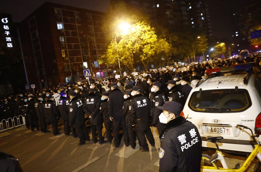 Des policiers bloquent une route, lors d'une manifestation déclenchée par un incendie qui a fait 10 morts, à Pékin.