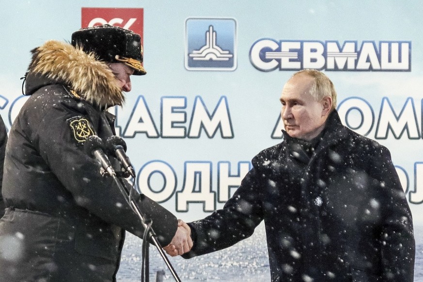 Russian President Vladimir Putin, right, shakes hands with Admiral Nikolai Yevmenov, Commander-in-Chief of the Russian Navy as he attends a flag-raising ceremony for newly-built nuclear submarines at  ...