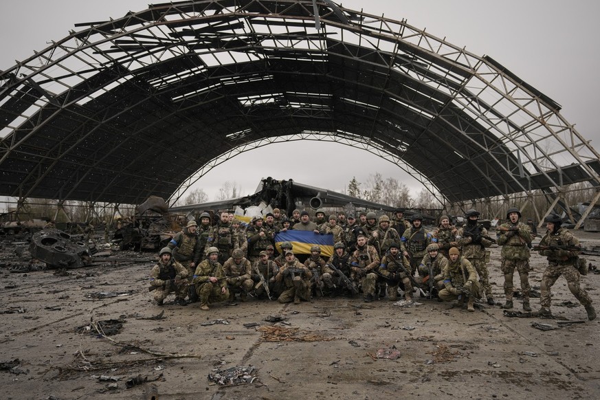 Ukrainian servicemen shout patriotic slogans backdropped by an Antonov An-225 Mriya aircraft destroyed during fighting between Russian and Ukrainian forces on the Antonov airport in Hostomel, Ukraine, ...