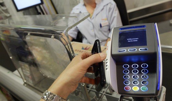 Eine Frau bezahlt mit dem Smartphone an der Kasse einer Coop Filiale in Zuerich am Dienstag, 1. Juli 2014. Mit &quot;Tapit&quot; kommt erstmals eine Smartphone App auf den Schweizer Markt, die das Bez ...