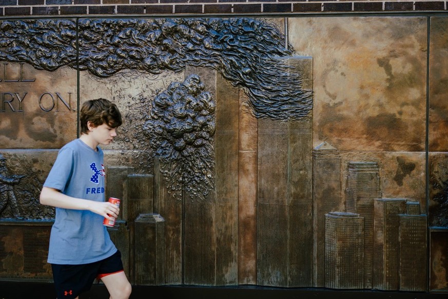 Un jeune garçon passe devant le mémorial en hommage aux pompiers new-yorkais morts en service lors des attentats du 11-Septembre. Ce bas-relief en bronze est apposé sur la façade de la caserne No 10 d ...