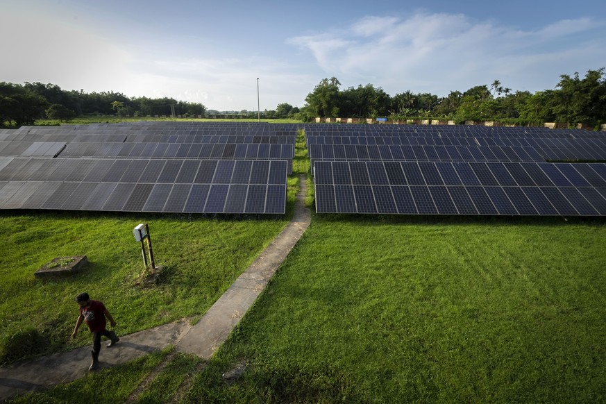 An employee walks away from solar panels near a hydrogen plant at Oil India Limited in Jorhat, India, Thursday, Aug. 17, 2023. Green hydrogen is being touted around the world as a clean energy solutio ...