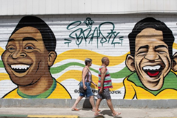 epa10308589 Tw people walk past a mural depicting Brazilian soccer legends Pele and Garrincha in Rio de Janeiro, Brazil, 16 November 2022. Brazilians have decorated some streets in their cities for th ...