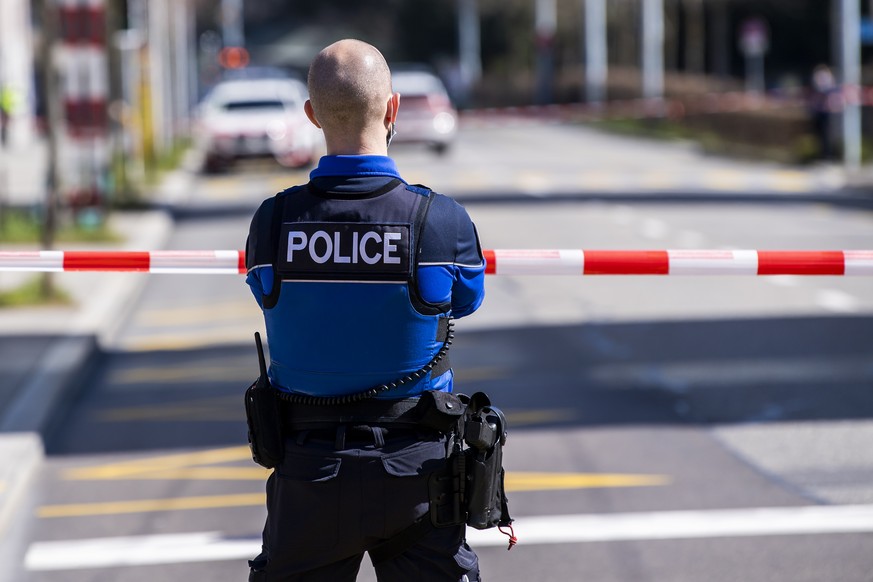 Un policier patrouille autour du gymnase de Beaulieu apres une alerte a la bombe le mercredi 24 mars 2021 a Lausanne. (KEYSTONE/Jean-Christophe Bott)