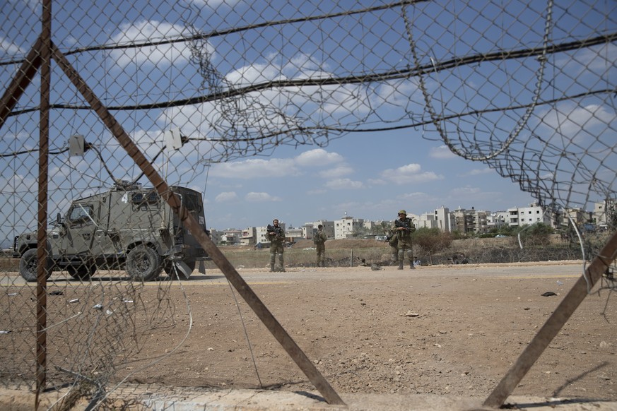 Israeli soldiers guard a damaged section of the Israeli separation fence, that is used by Palestinian laborers to cross into Israel, in the West Bank village of Jalameh, near Jenin, Monday, Sept. 6, 2 ...