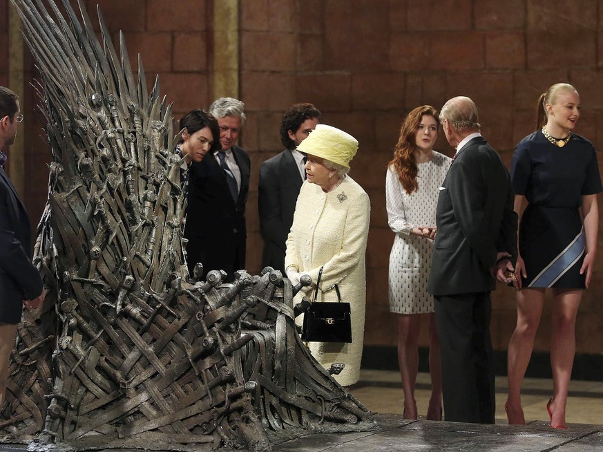Britain&#039;s Queen Elizabeth looks at the Iron Throne as Prince Philip (2nd R) greets cast member Rose Leslie (3rd R) on the set of the television series Game of Thrones, in the Titanic Quarter of B ...