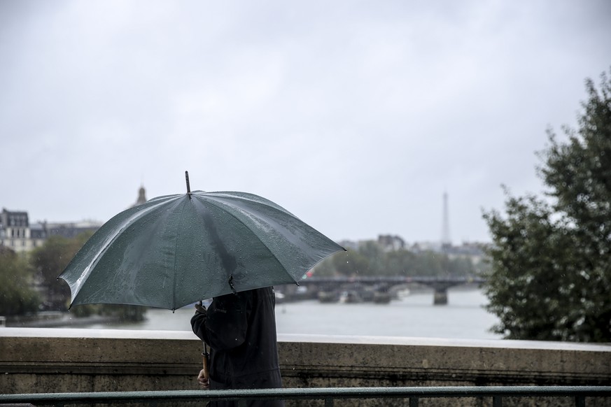 epa11650950 A man with an umbrella walks across a bridge in Paris, France, 09 October 2024. Storm Kirk has caused major disruptions in France&#039;s southwest, resulting in high winds and flooding. In ...
