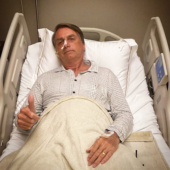 epa09664994 An image taken from Brazilian President Jair Bolsonaro's official Twitter feed showing him giving the thumbs-up from his hospital bedafter being admittedd for an abdominal problem, in Sao  ...
