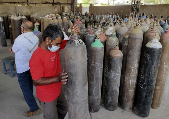 Workers load oxygen cylinders at a charging station on the outskirts of Prayagraj, India, Friday, April 23, 2021. India put oxygen tankers on special express trains as major hospitals in New Delhi on  ...