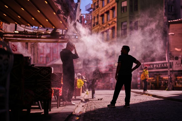 Waiters stand to invite passersby to a restaurant as water is sprayed to cool the area on a hot day in Istanbul, Turkey, Thursday, June 11, 2026. (AP Photo/Francisco Seco)
Turkey Extreme Weather Heat