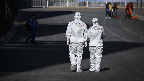 Olympic workers walk on a road at the Olympic Village ahead of the 2022 Winter Olympics, Tuesday, Feb. 1, 2022, in Beijing. (Wang Zhao/Pool Photo via AP)