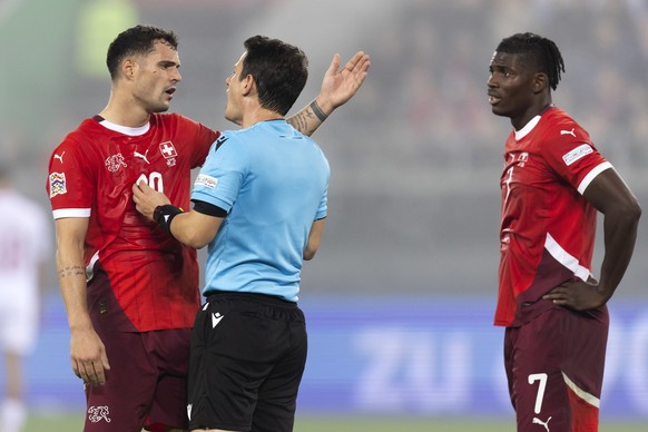 Switzerland&#039;s Granit Xhaka, left, and Breel Embolo, right, discuss with referee Halil Umut Meler during the UEFA Nations League Group D soccer match between Switzerland and Denmark, on Tuesday, O ...
