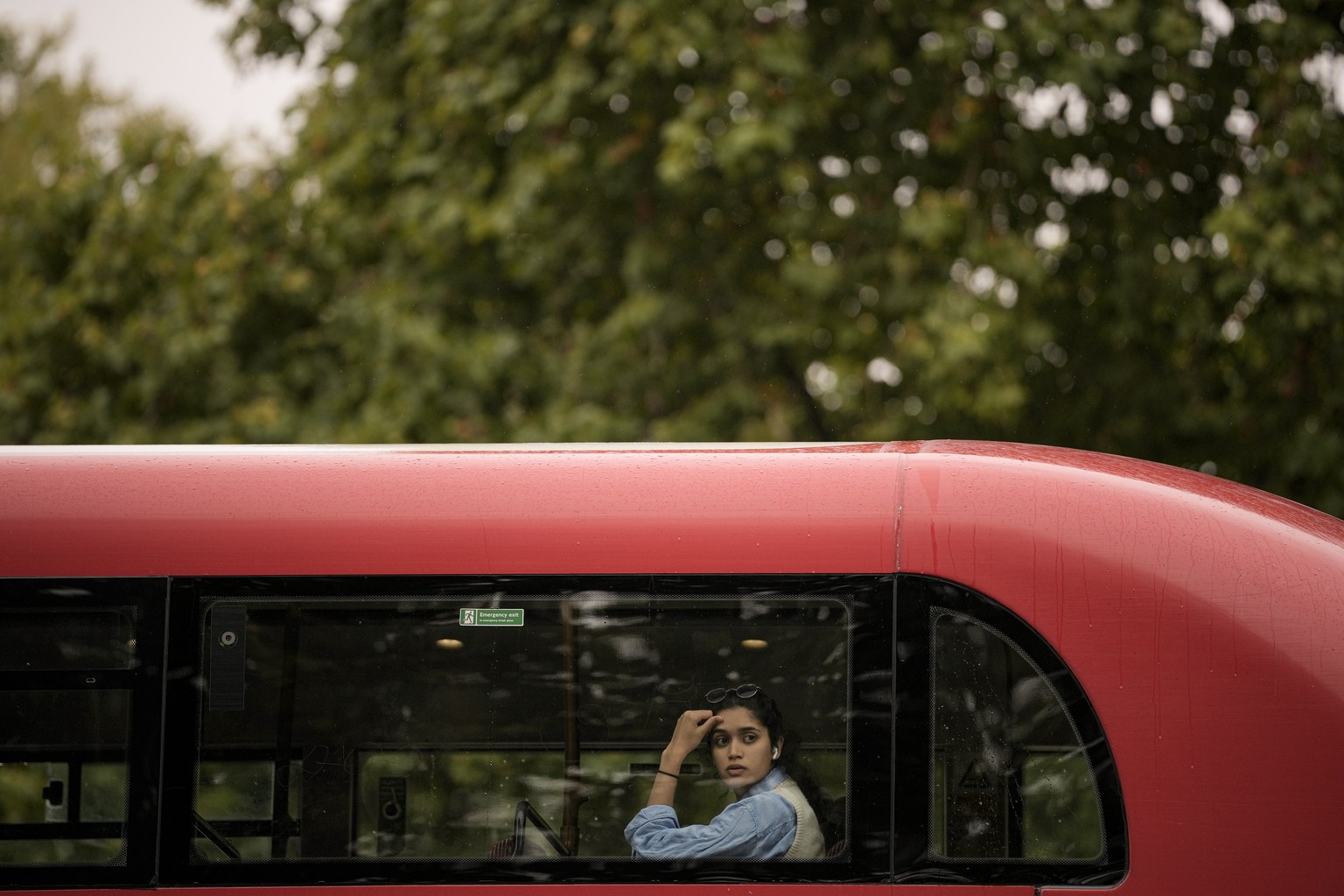 A woman looks from a bus at people lining up the street to see the State Hearse carrying the coffin of Queen Elizabeth II on its way to Buckingham Palace in London, Tuesday, Sept. 13, 2022. Queen Eliz ...