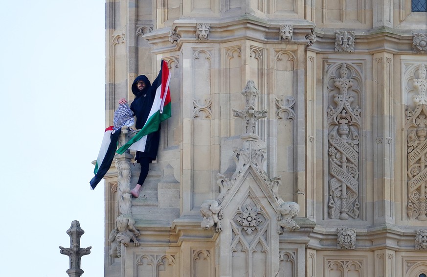 epa11948802 A pro-Palestinian protester waves a Palestinian flag atop the Elizabeth Tower in London, Britain, 08 March 2025. Police and emergency services try to coax a Palestinian protester down from ...