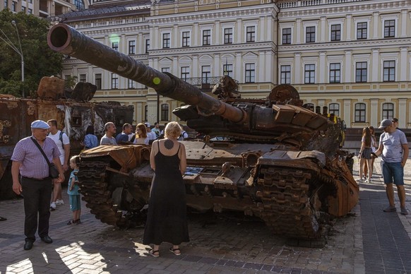 Les gens regardent un char russe qui a été détruit lors de combats avec l'armée ukrainienne, exposé sur la place Mykhailivskyi, à Kyiv, Ukraine, le 12 juin 2022. Le 24 février, les troupes russes ...