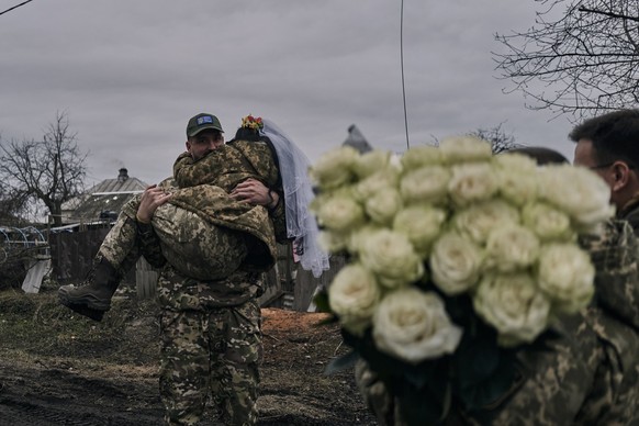 Ukrainian army medic Oleksander carries his bride and comrade Eugenia after their wedding ceremony in Lyman, Donetsk region, Ukraine, Saturday, Dec. 24, 2022. (AP Photo/Felipe Dana)