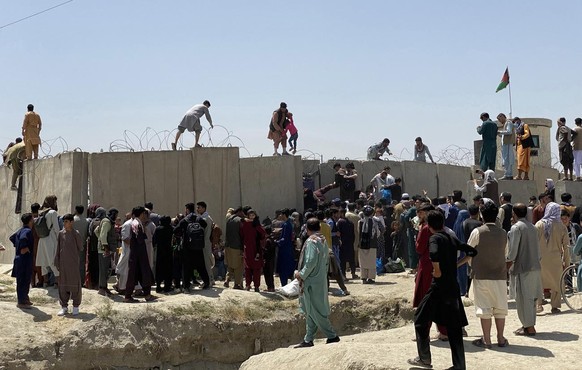 epa09416177 People struggle to cross the boundary wall of Hamid Karzai International Airport to flee the country after rumors that foreign countries are evacuating people even without visas, after Taliban took control of Kabul, Afghanistan, 16 August 2021. Taliban co-founder Abdul Ghani Baradar Monday declared victory and end to the decades-long war in Afghanistan, a day after the insurgents entered Kabul to take control of the country. Baradar, who heads the Taliban political office in Qatar, released a short video message after President Ashraf Ghani fled and conceded that the insurgents had won the 20-year war. EPA/STRINGER