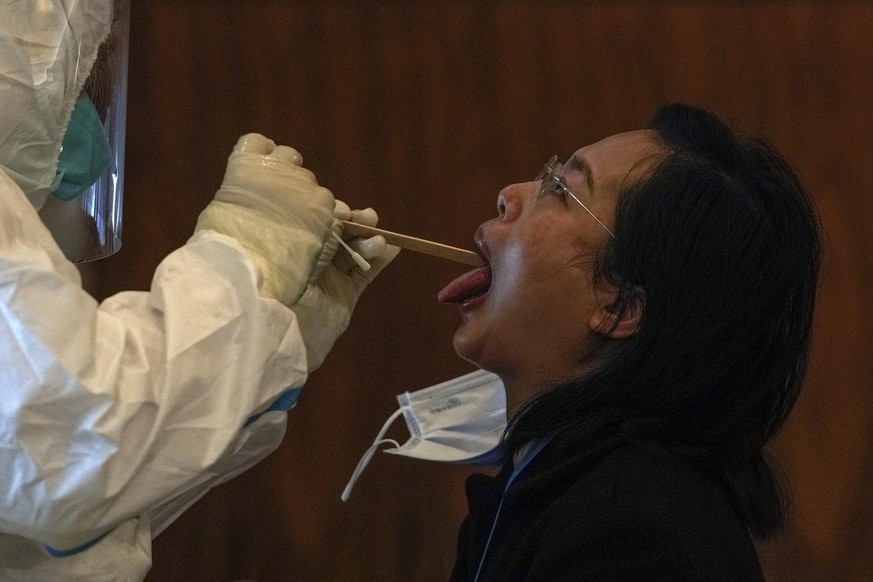 A medical worker collects a sample from a reporter taking part in the Beijing Winter Olympics torch relay activities at a coronavirus test site in Beijing, Wednesday, Feb. 2, 2022. With more than 30 n ...