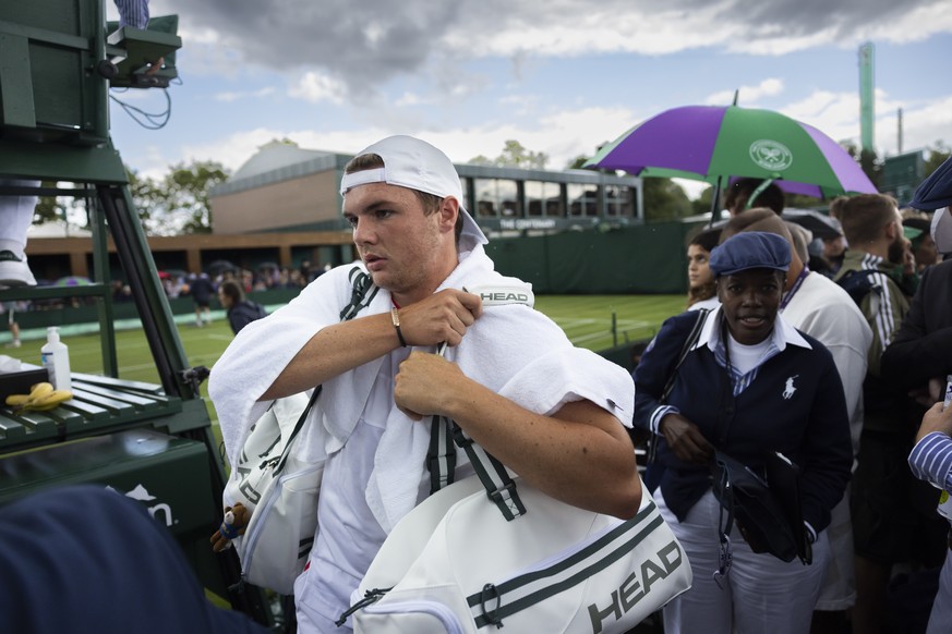 Dominic Stricker of Switzerland leaves the court while play is suspended due to rain during his first round match against Alexei Popyrin of Australia at the All England Lawn Tennis Championships in Wi ...