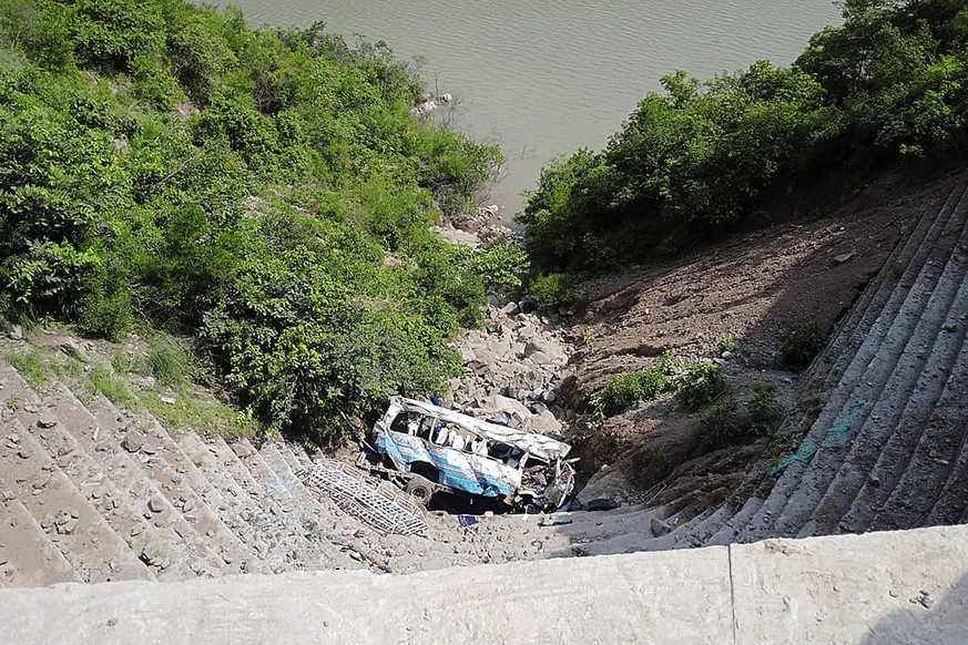 The wreckage of a bus is seen after falling into a ravine, near Kahuta, Pakistan, Sunday, Aug. 25, 2024. (AP Photo/Mohammad Yousaf)
