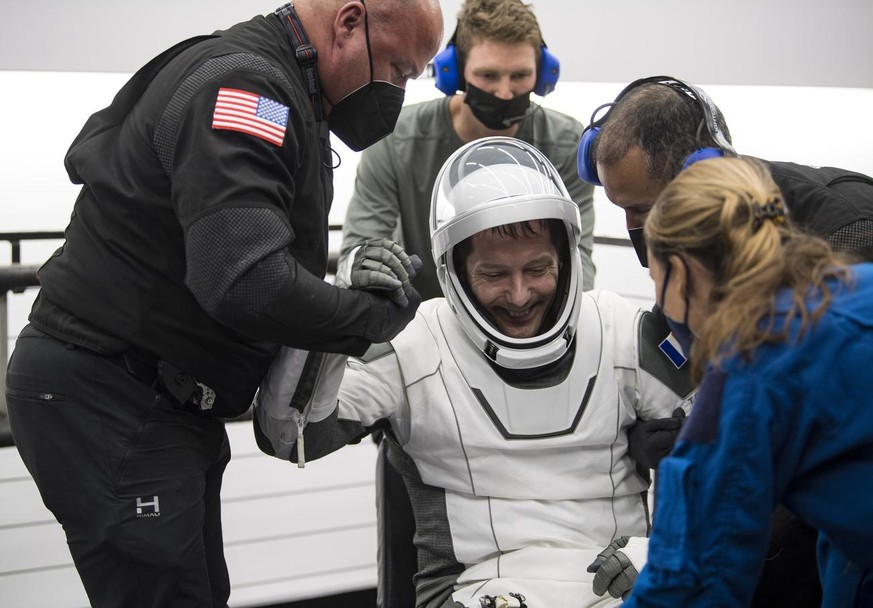 In this photo provided by NASA, European Space Agency astronaut Thomas Pesquet is helped out of the SpaceX Crew Dragon Endeavour spacecraft onboard the SpaceX GO Navigator recovery ship after he and N ...