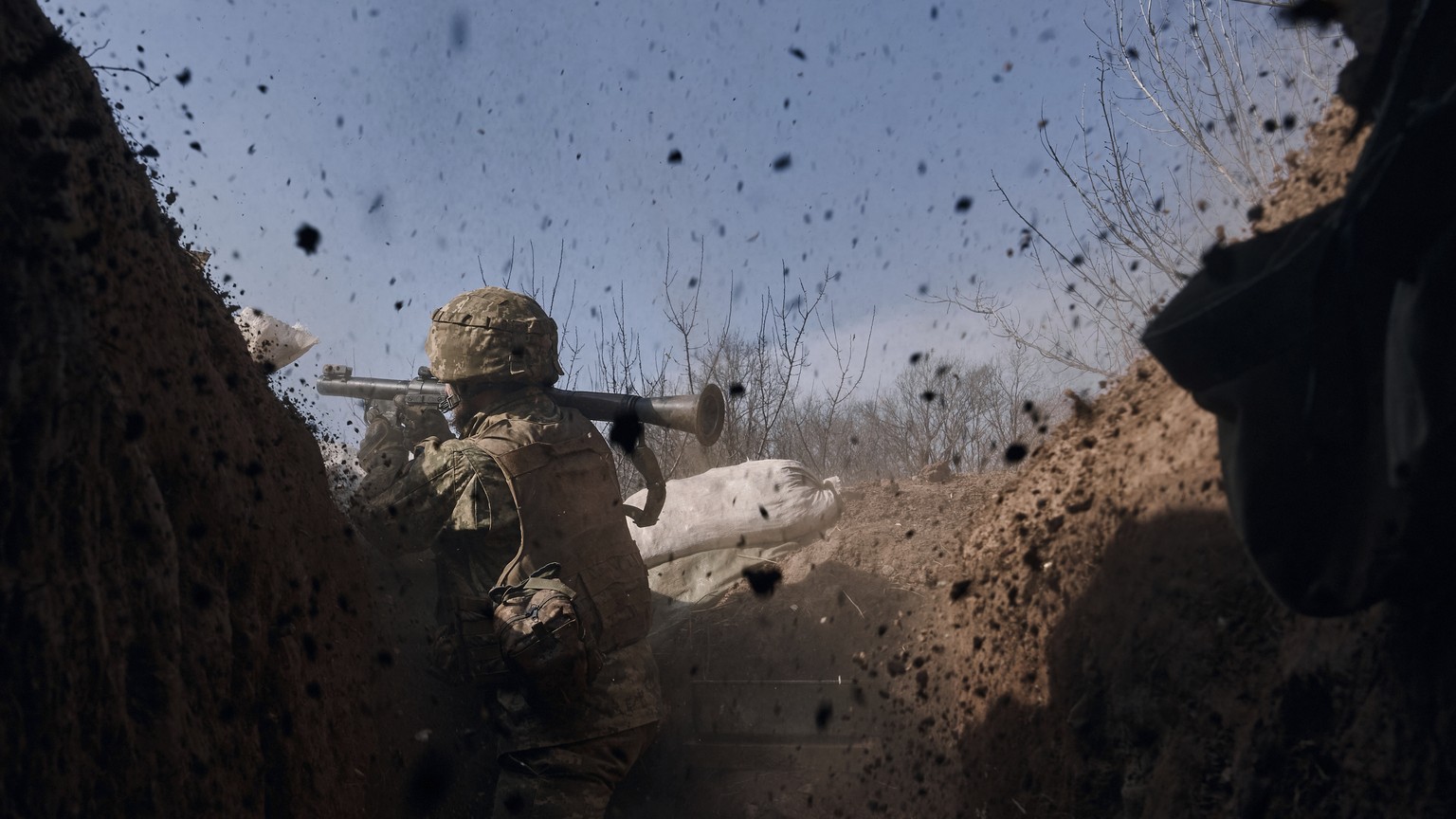 A Ukrainian soldier of the 28th brigade fires a grenade launcher on the frontline during a battle with Russian troops near Bakhmut, Donetsk region, Ukraine, Friday, March 24, 2023. (AP Photo/Libkos)