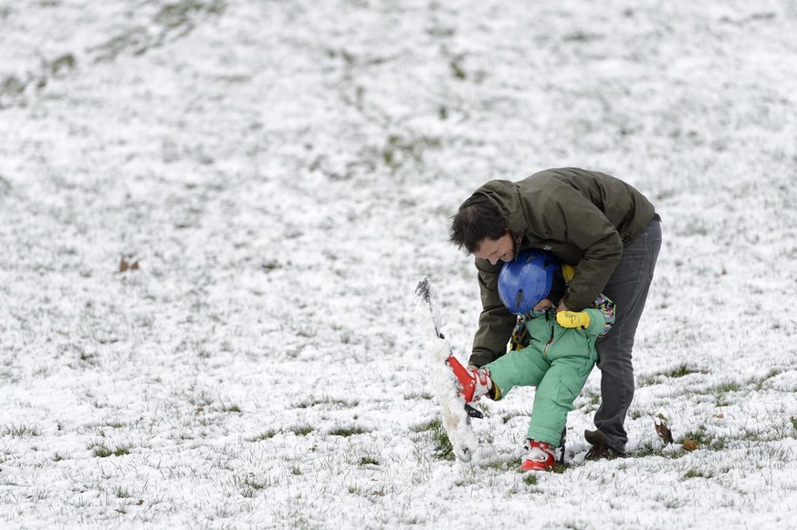 Un père et son fils Romero l'aide a faire du ski, ce dimanche 17 janvier 2016 a Genève. La neige a refait son apparition jusque en plaine dans la matinee (2016).