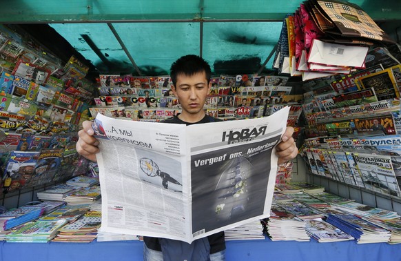 epa04329973 A vendor looks through Novaya Gazeta newspaper in Moscow, Russia, 25 July 2014. The edition frontpage contains a picture of a convoy of funeral hearses carrying the remains of the victims ...