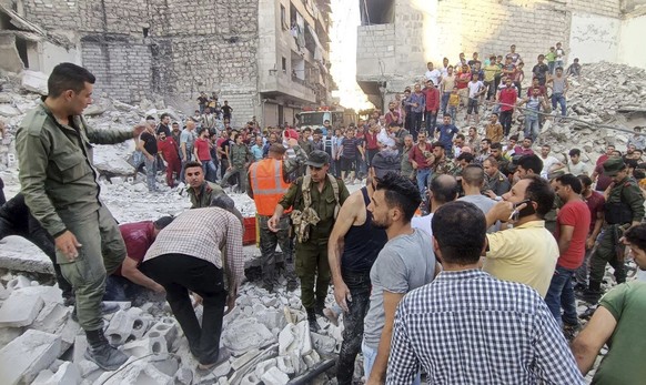 In this photo released by the Syrian official news agency SANA, shows Syrian Civil Defense workers and security forces search for victims under the rubble of a destroyed building, in Aleppo, Syria, We ...
