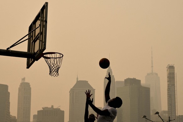 People play basketball as wildfire smoke from Canada causes hazy conditions on July 16, 2026 in New York. Out-of-control wildfires were raging Thursday in the Canadian province of Ontario, prompting e ...