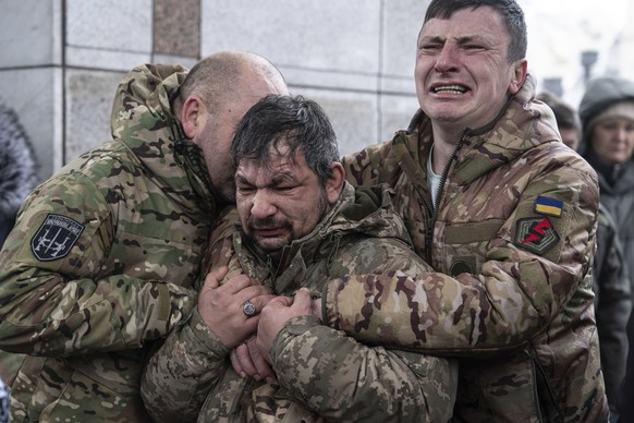 Ukrainian servicemen cry near the coffin of their comrade Andrii Trachuk during his funeral service on Independence square in Kyiv, Ukraine, Friday, Dec. 15, 2023. Trachuk was a veteran of Revolution  ...