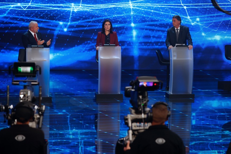 epa10144592 Brazilian President Jair Bolsonaro (R) and his main rival, former president Luiz Inacio Lula da Silva (L) and candidate Simone Tebet (C) participate in a debate at the television headquart ...