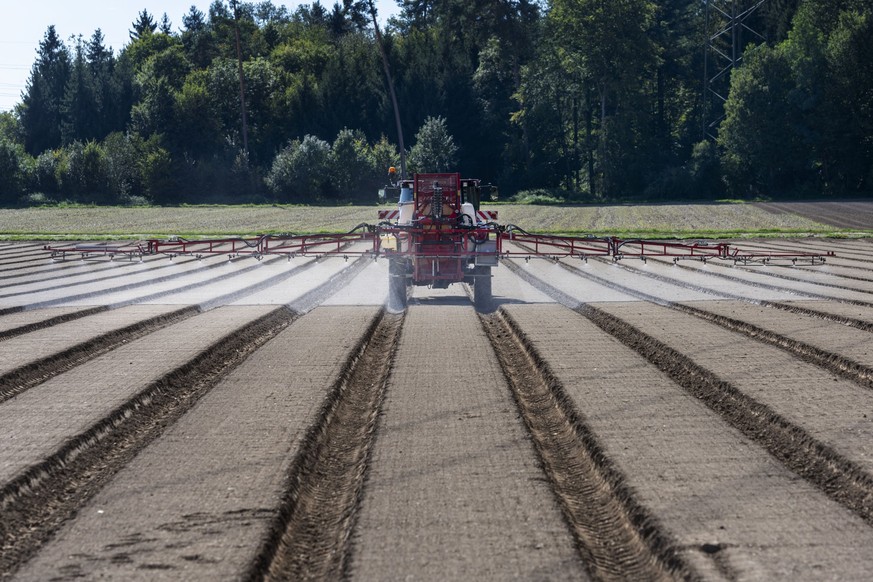 After the spinach seeds were sown in a field on the Gemuese Kaeser &amp; Co. farm in Birmenstorf, Switzerland, a tractor with a field sprayer system applies a herbicide which reduces the germination o ...