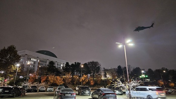 epa11754572 A helicopter hovers over the National Assembly in Seoul shortly after South Korean President Yoon Suk Yeol declared martial law in Seoul, South Korea, 03 December 2024. South Korean Presid ...