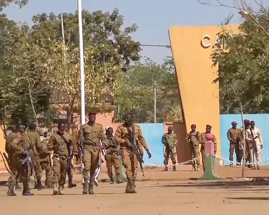 In this image made from video, Burkina Faso mutinous soldiers walk outside the Guillaume Ouedraogo military camp in Ouagadougou, Monday Jan. 24, 2022. Mutinous soldiers said they detained Burkina Faso ...
