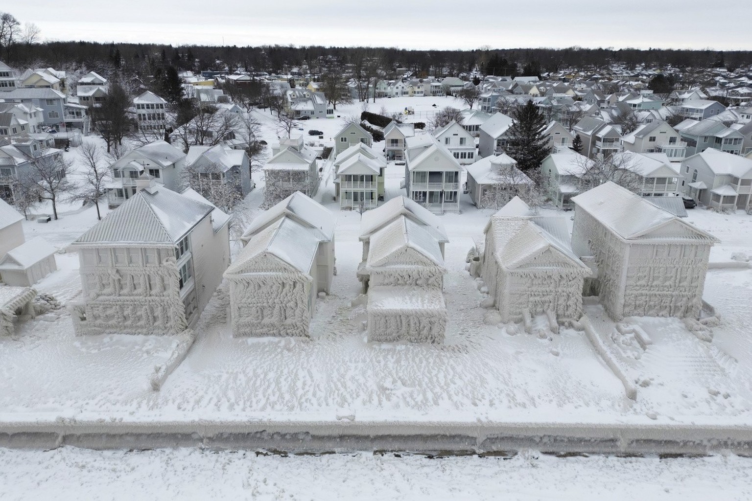 In this image taken by drone, houses along the shores of Lake Erie, near Fort Erie, Ontario, remain covered in ice Tuesday, Dec. 27, 2022, following a winter storm that swept through much of Ontario.  ...