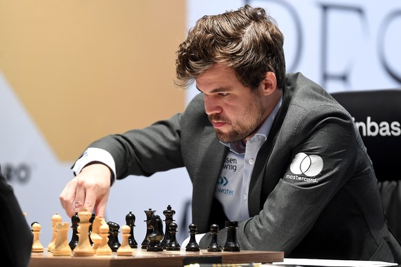 epa09633984 Defending Champion Magnus Carlsen of Norway plays against Ian Nepomniachtchi (not pictured) of Russia during the 11th round of FIDE World Chess Championship at the EXPO 2020 Dubai in Dubai ...