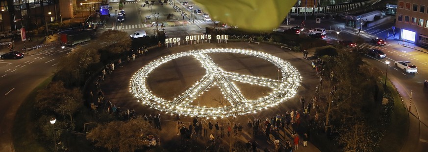 epaselect epa09842836 A Ukrainian flag flies above a giant Peace sign set up by Avaaz activists with placards &#039;Stop Putin&#039;s oil&#039; during a protest against Russian invasion of Ukraine in  ...