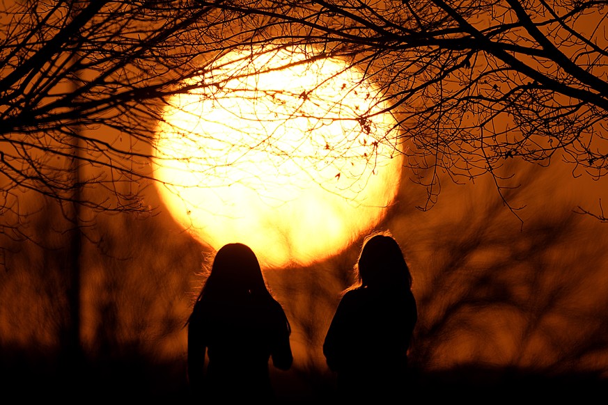 Des gens regardent le coucher de soleil dans un parc par une journée anormalement chaude, le 25 février 2024, à Kansas City.