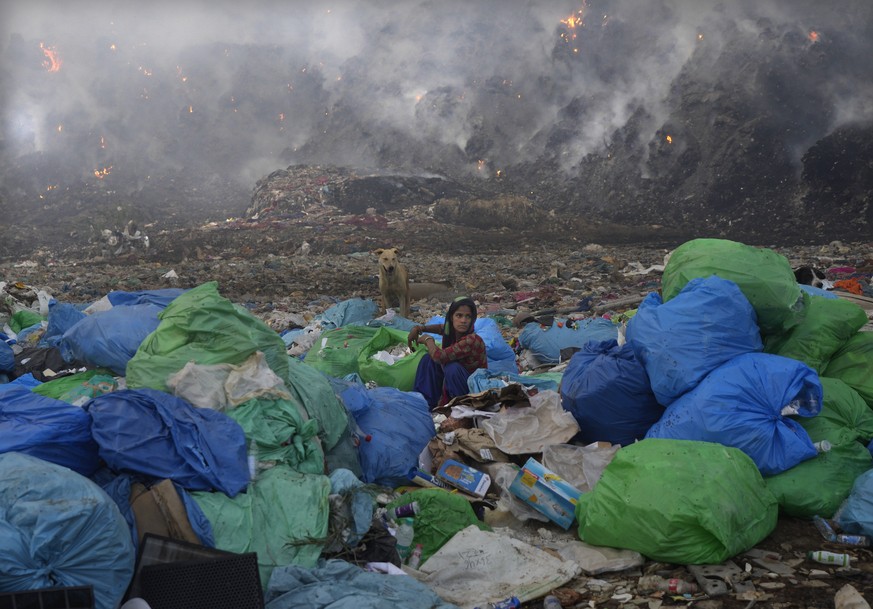 A ragpicker woman segregates items sitting at the edge during a fire at the Bhalswa landfill in New Delhi, India, Wednesday, April 27, 2022. India&#039;s capital, which like the rest of South Asia is  ...