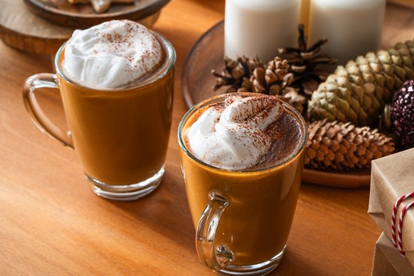 Still life of Christmas cozy home with two mugs of pumpkin spice latte with whipped cream, close up