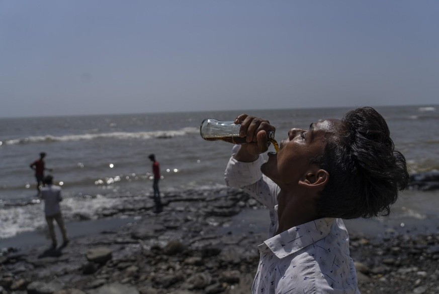Un garçon boit un soda sur une promenade sur la côte de la mer d'Arabie à Mumbai, en Inde, dimanche 1er mai 2022.