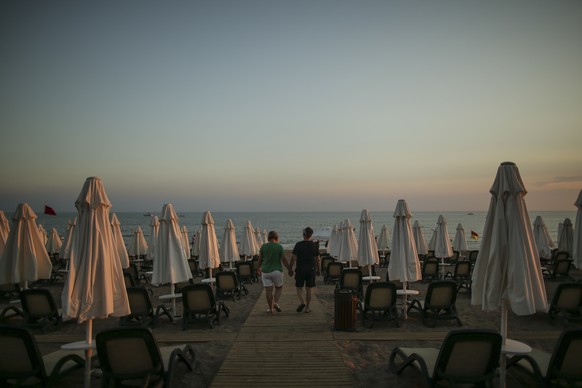 Tourists walk at the beach of Antalya, southern Turkey, as the sun sets, on Sunday, June 20, 2021. Hotels in Turkey&#039;s Antalya region, a destination beloved by holidaymakers, are preparing to fina ...