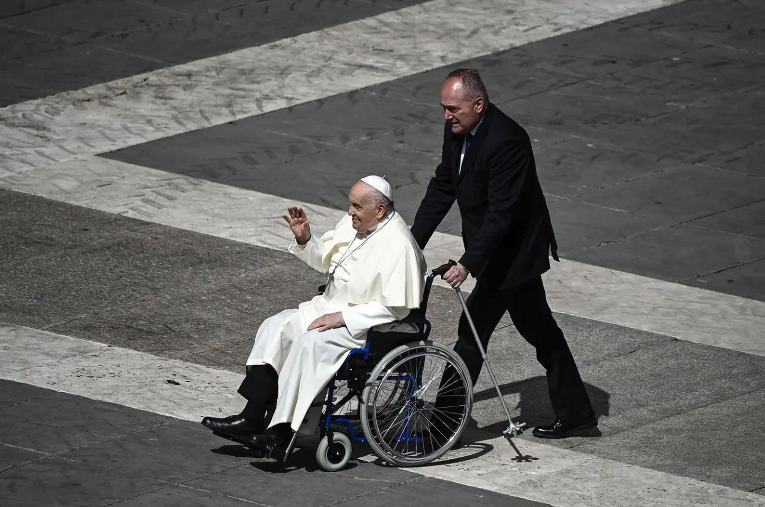 Le Pape salue les fidèles depuis son fauteuil roulant.