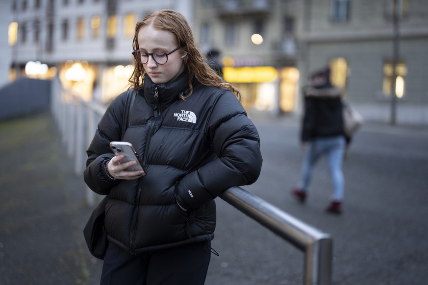 Lin, liest die News auf Instagram auf ihrem Handy, fotografiert am Montag, 10. Februar 2025 in Fribourg. (KEYSTONE/Gaetan Bally)