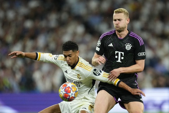 Real Madrid's Jude Bellingham, left, challenges for the ball with Bayern's Matthijs de Ligt during the Champions League semifinal second leg soccer match between Real Madrid and Bayern Munic ...